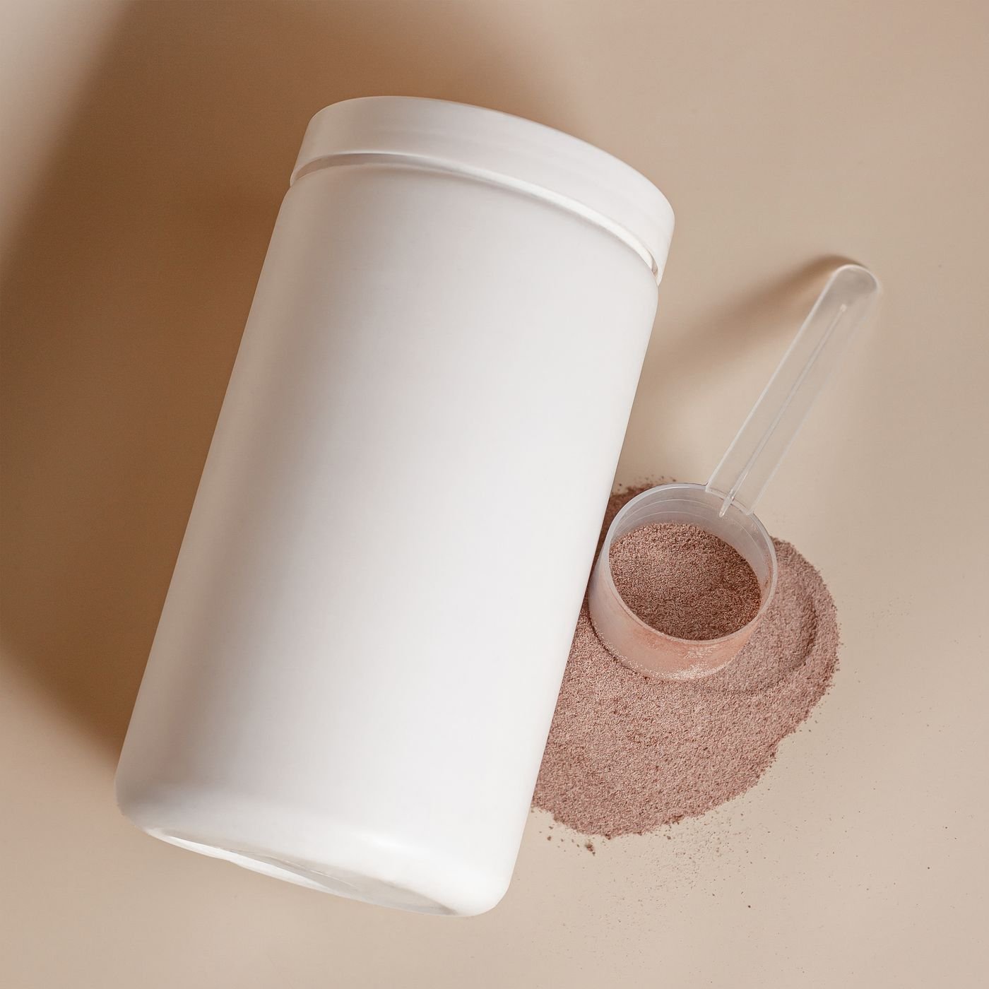 Supplement tub lying on its side with a scoop of powder beside it