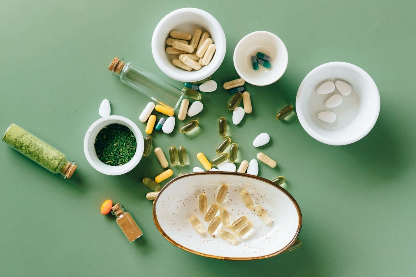 Assorted supplement capsules and powders arranged on a green surface