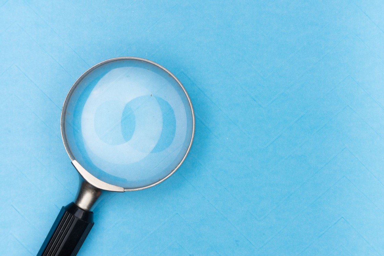 Magnifying glass held over research documents