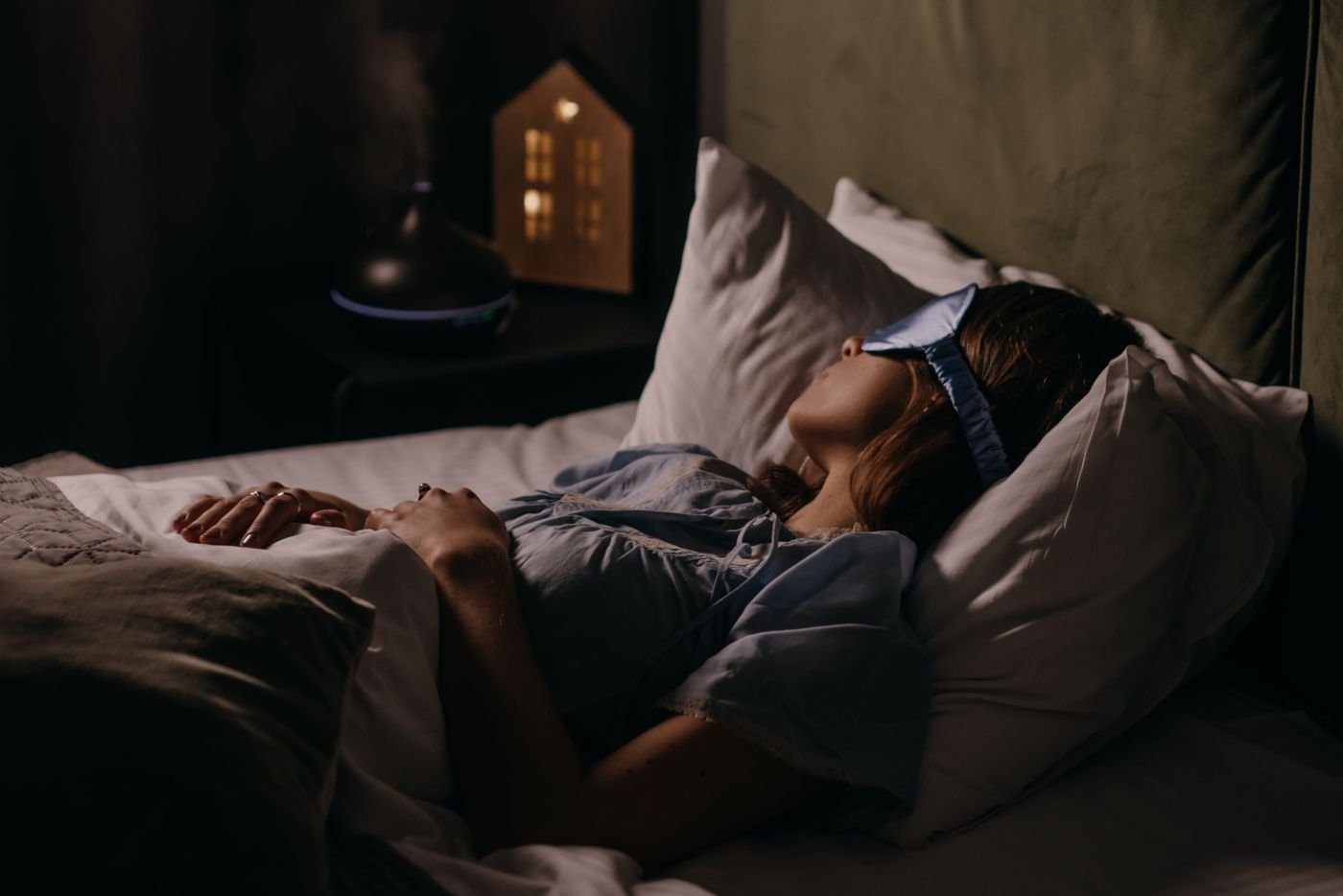 Person asleep in bed at night wearing a sleep mask
