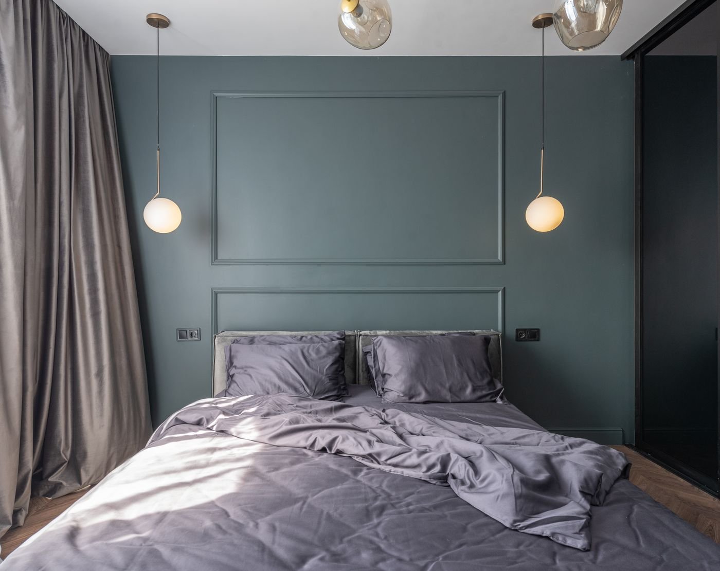 Dimly lit bedroom with a made bed and warm pendant lighting